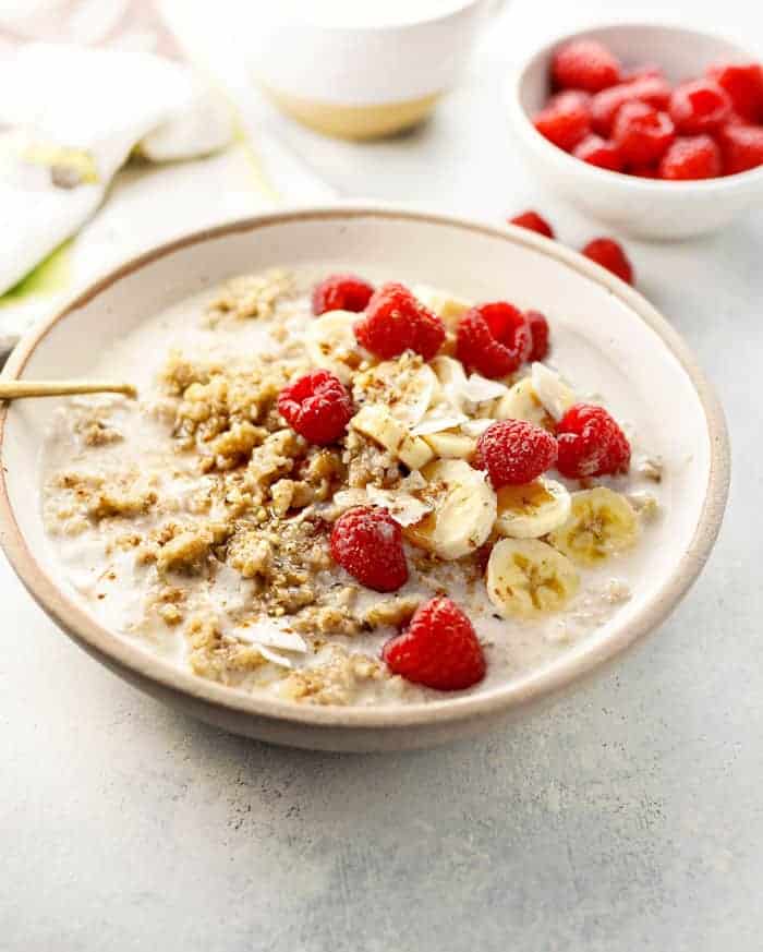 A bowl of breakfast quinoa garnished with bananas and raspberries.