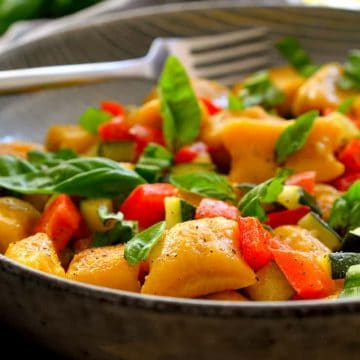 This vegan pumpkin gnocchi is easy to make with just a few simple ingredients. Served with a garlicky zucchini-red pepper sauce and fresh basil sprinkled on top, this colourful dish is a prime example of how simple is best!