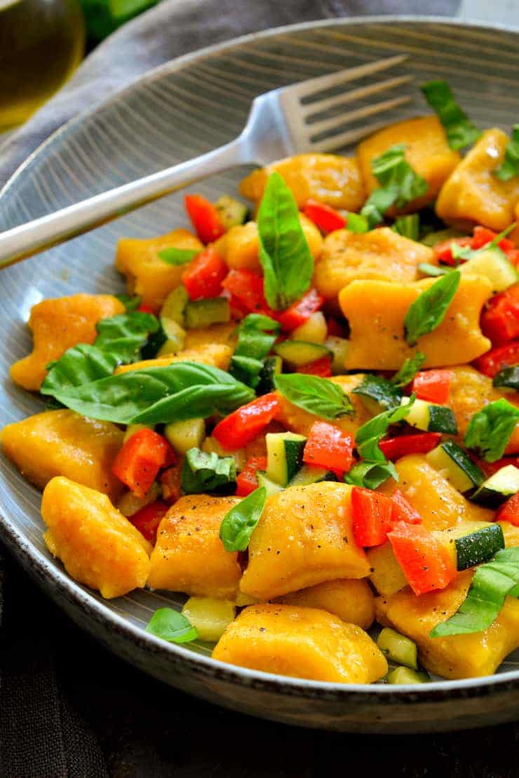 This vegan pumpkin gnocchi is easy to make with just a few simple ingredients. Served with a garlicky zucchini-red pepper sauce and fresh basil sprinkled on top, this colourful dish is a prime example of how simple is best!