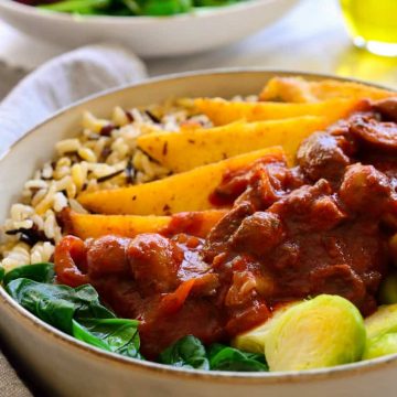 Vegan mushroom stew with fried polenta in a bowl of rice and greens.