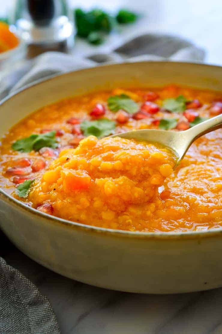 A spoonful of vegan lentil soup in a bowl.