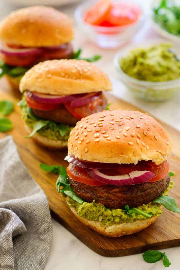 Three vegetarian sliders on a try with mint-pea pesto in a bowl.