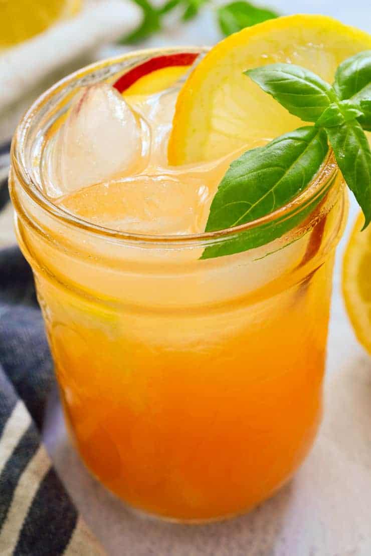 Peach nectar lemonade in a mason jar garnished with lemon and basil.