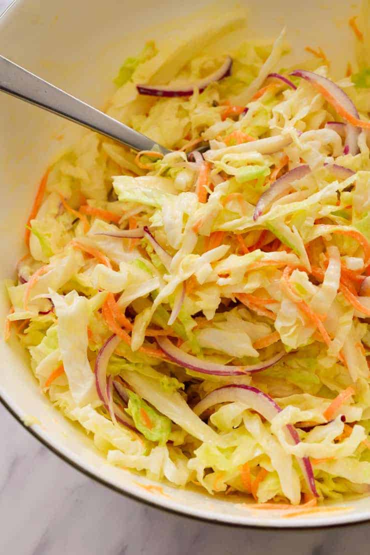Vegan coleslaw in a bowl mixed with the dressing.