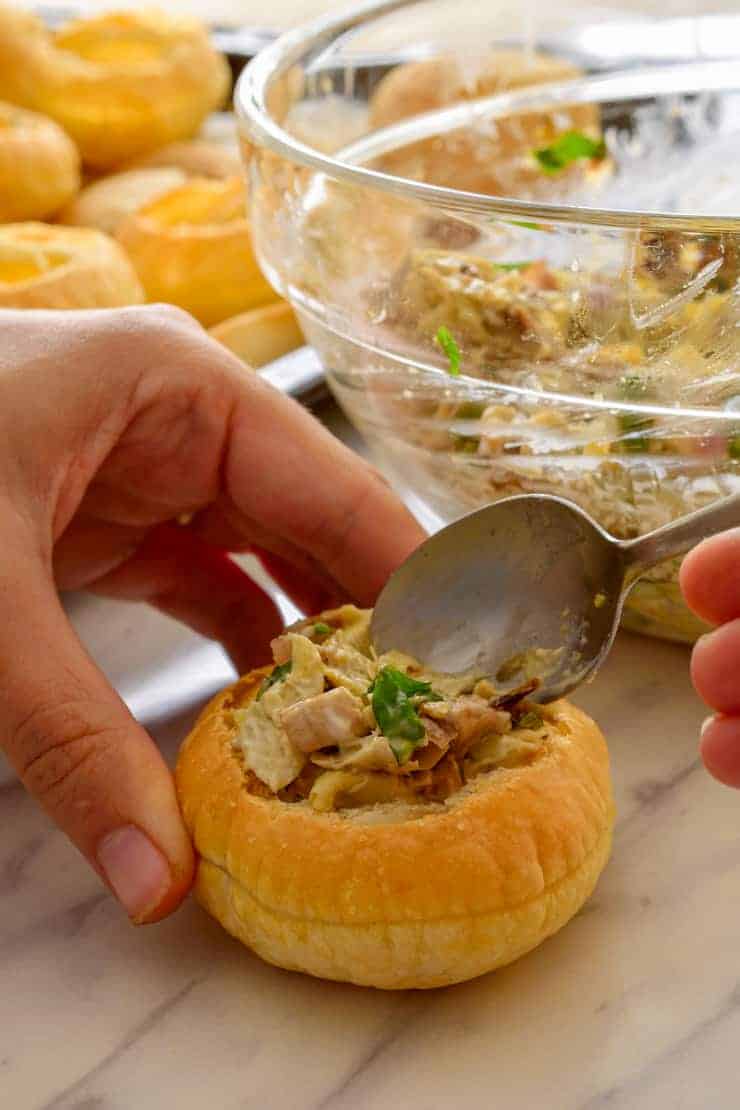 Filling a puff pastry cup with a spoon.