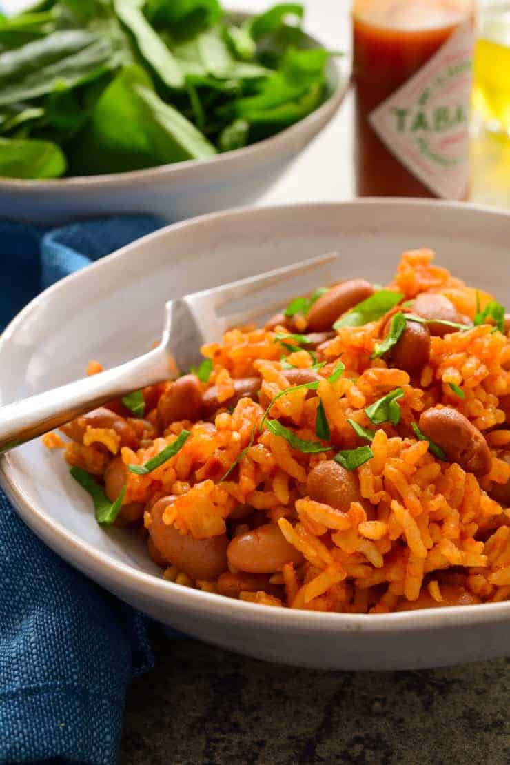 arroz e feijão espanhóis em uma tigela azul clara com um garfo.