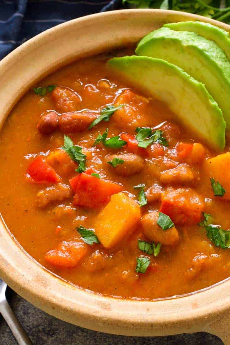 A overhead shot of the Pumpkin Chili in a brown bowl garnished with avocado.