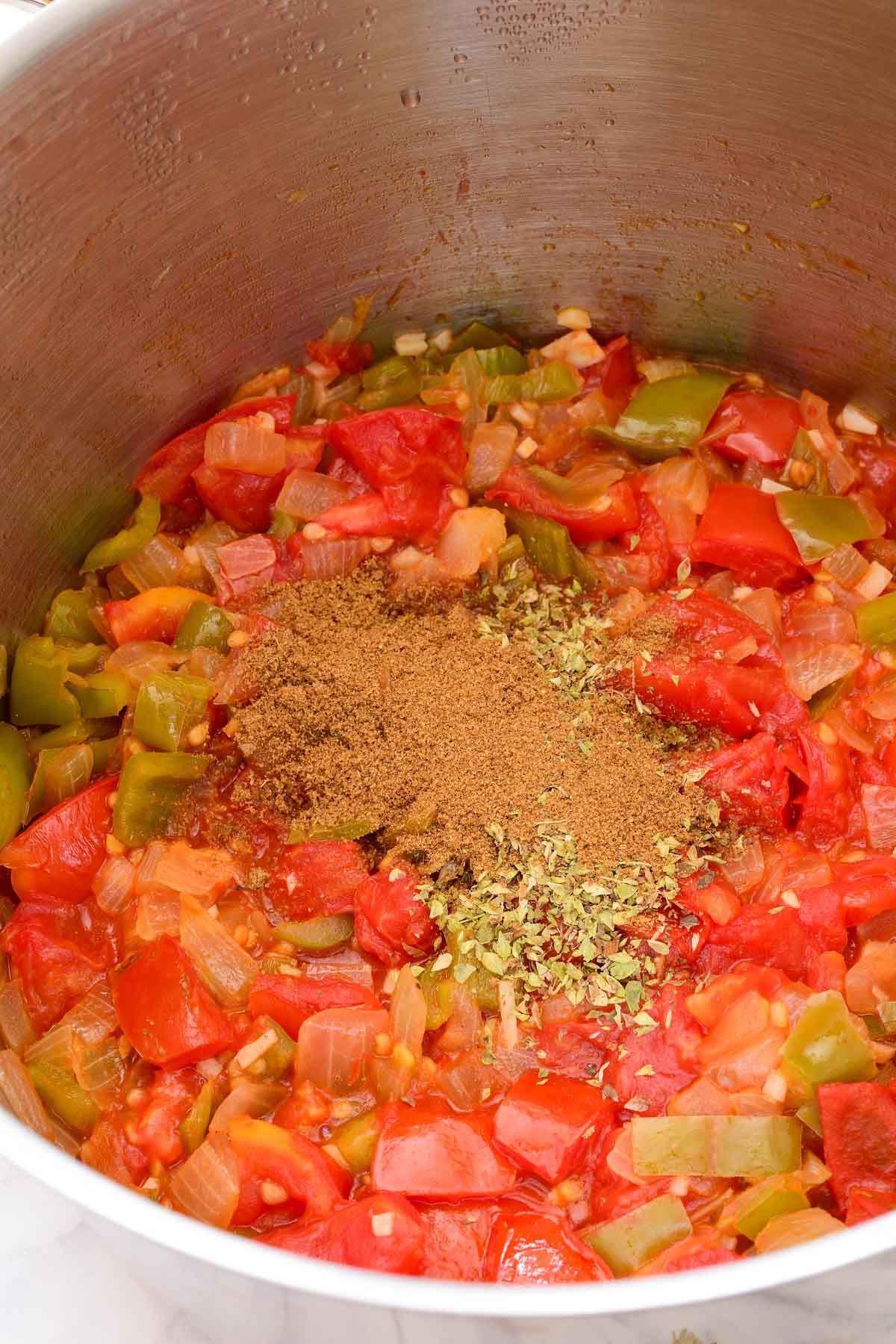 The sofrito inside the pot with cumin and oregano on top.