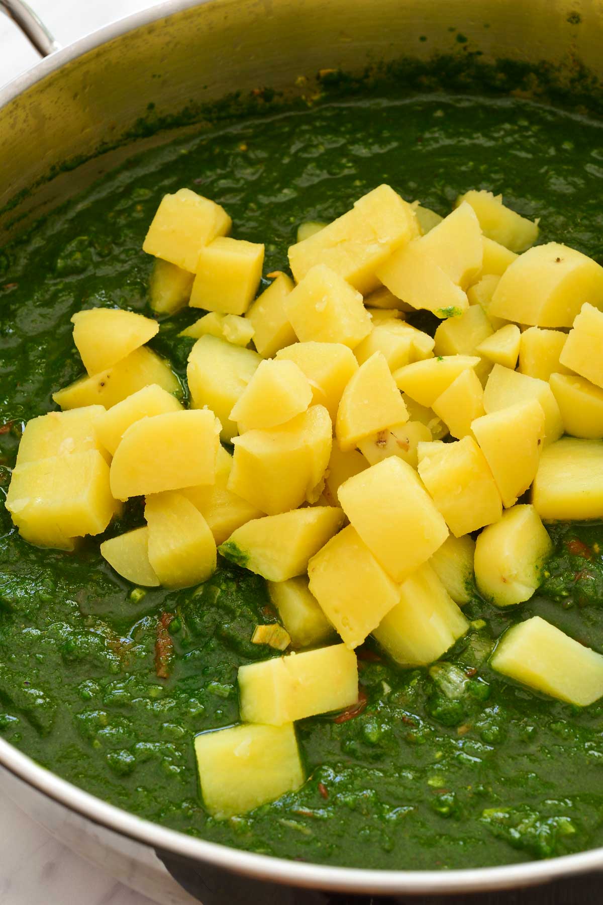 Inside the pot of spinach sauce with cubes of potato ready to be mixed in.