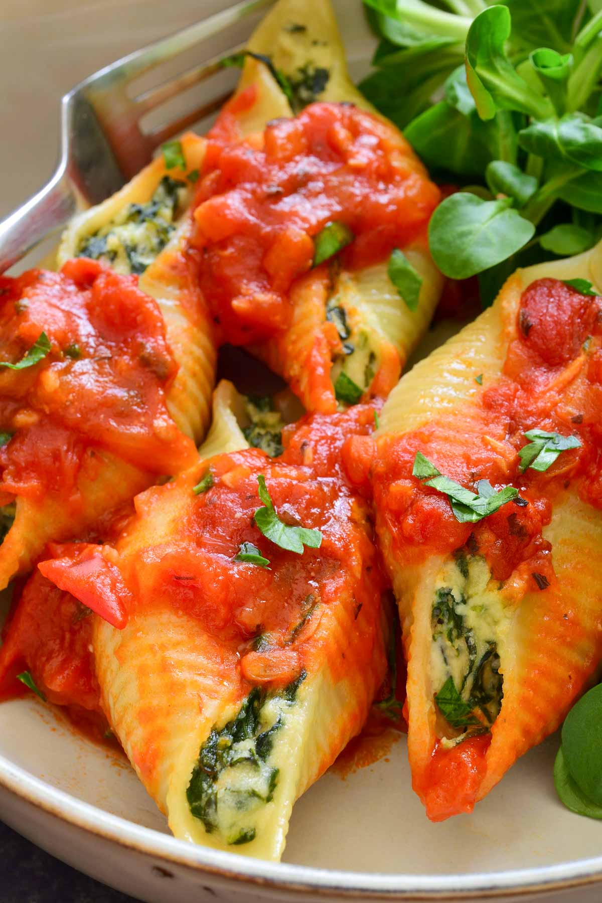 A close-up photo of four vegan stuffed shells in a grey bowl.
