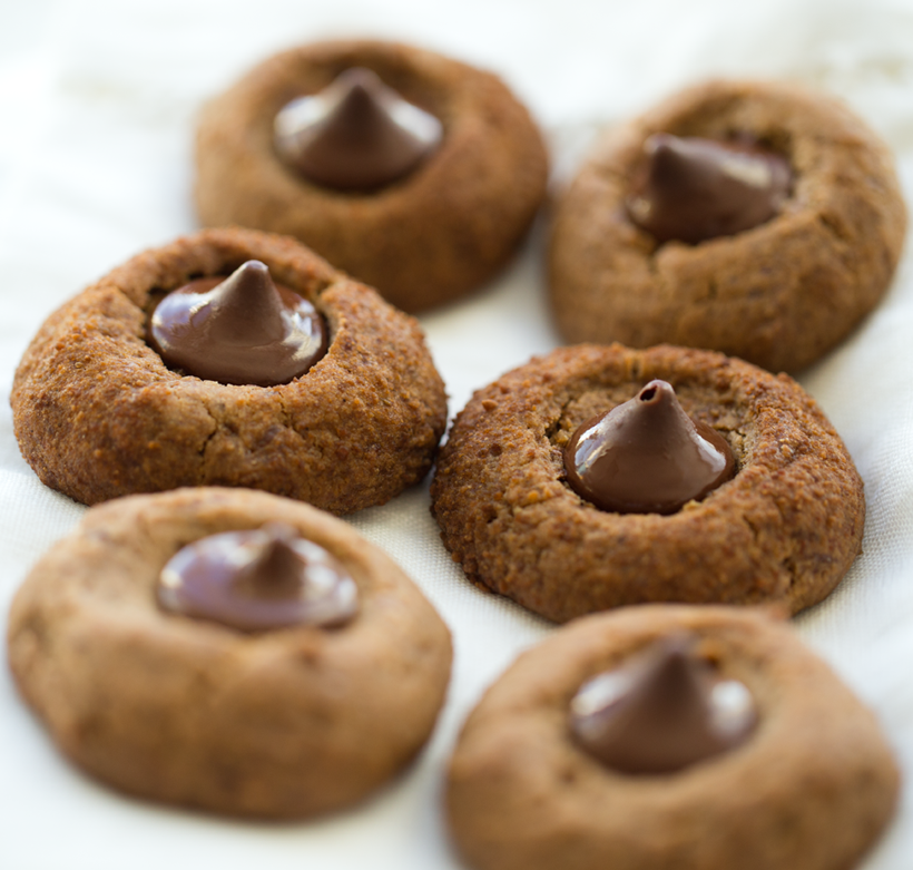 A close-up photo of six peanut butter cookies with a chocolate kiss in the middle of each.