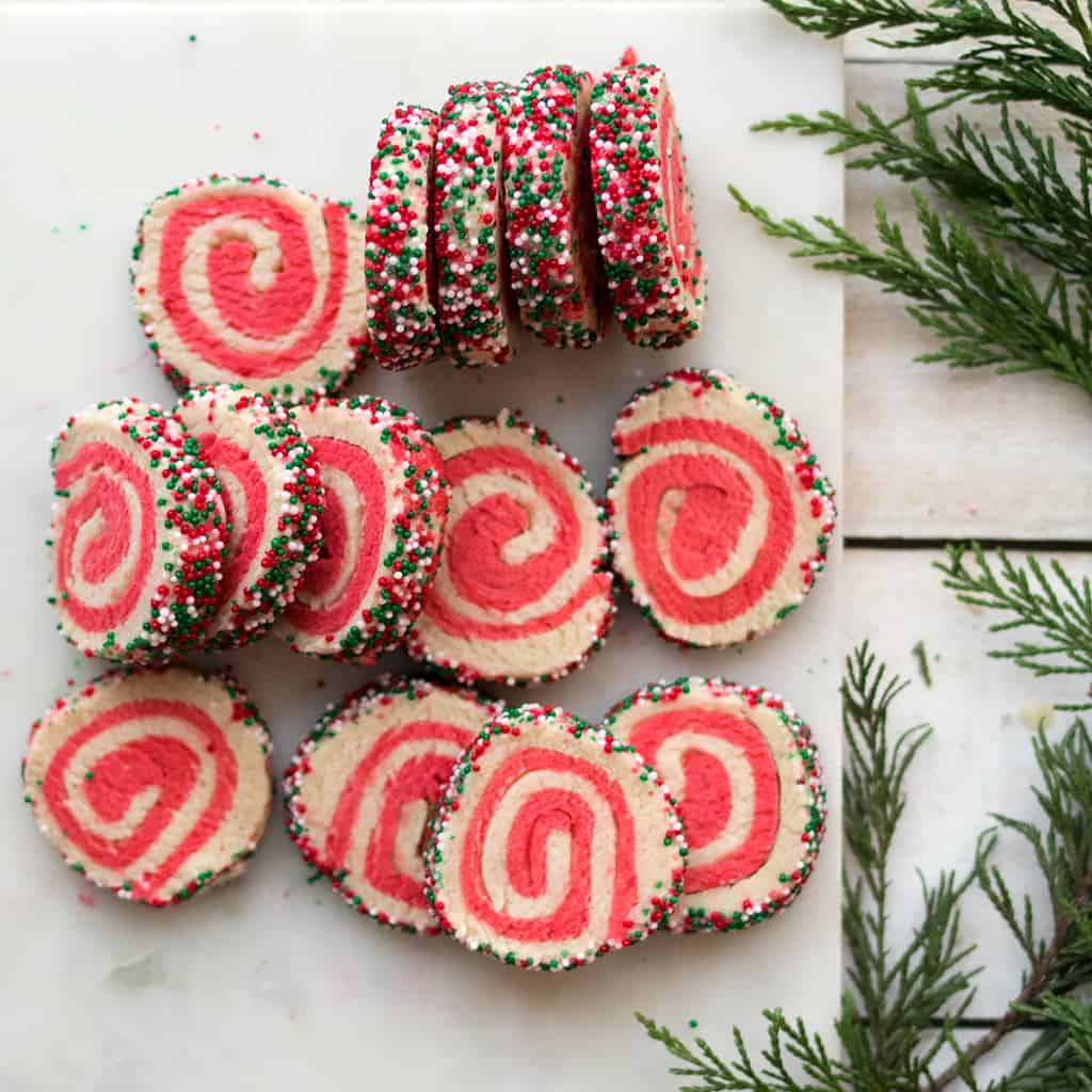 Pink and white pinwheel cookies with sprinkles around the edges.