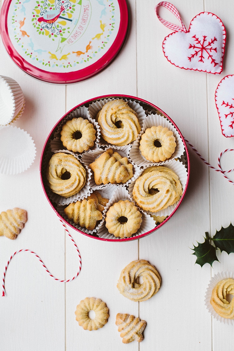 A tin box filled with Danish butter cookies in circular and tree shapes.