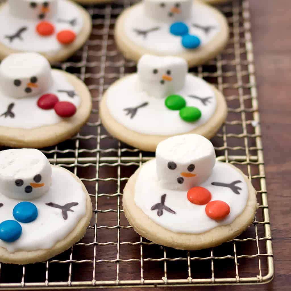 Cookies with marshmallow and icing made to look like a melting snowman on a cooling rack.