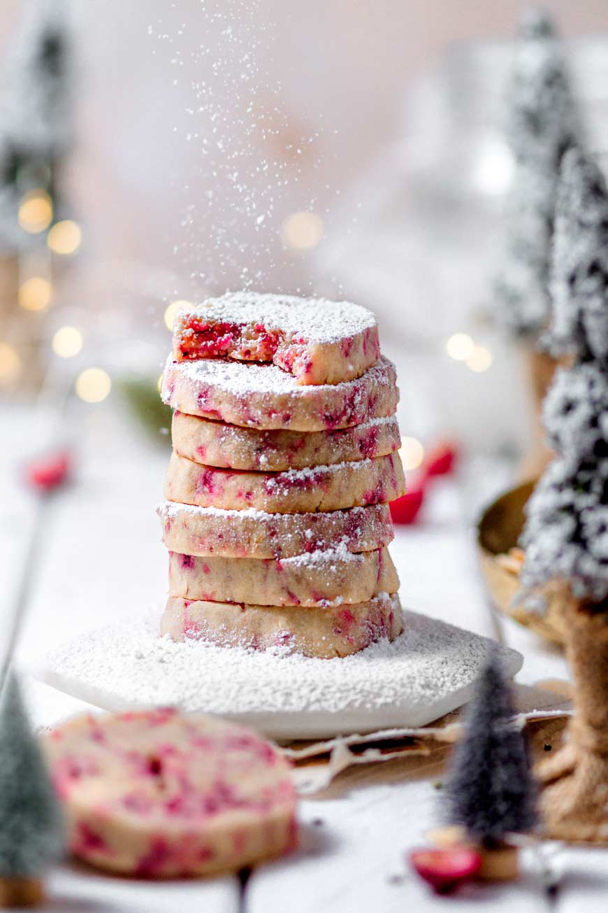Icing sugar sprinkling over a stack of cranberry shortbread cookies.