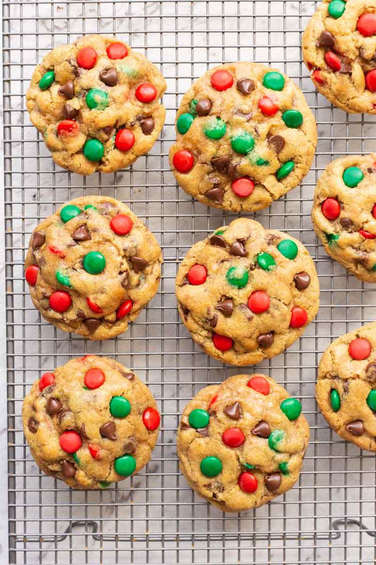 Cookies with chocolate chips and red and green m and m's on a cooling rack.