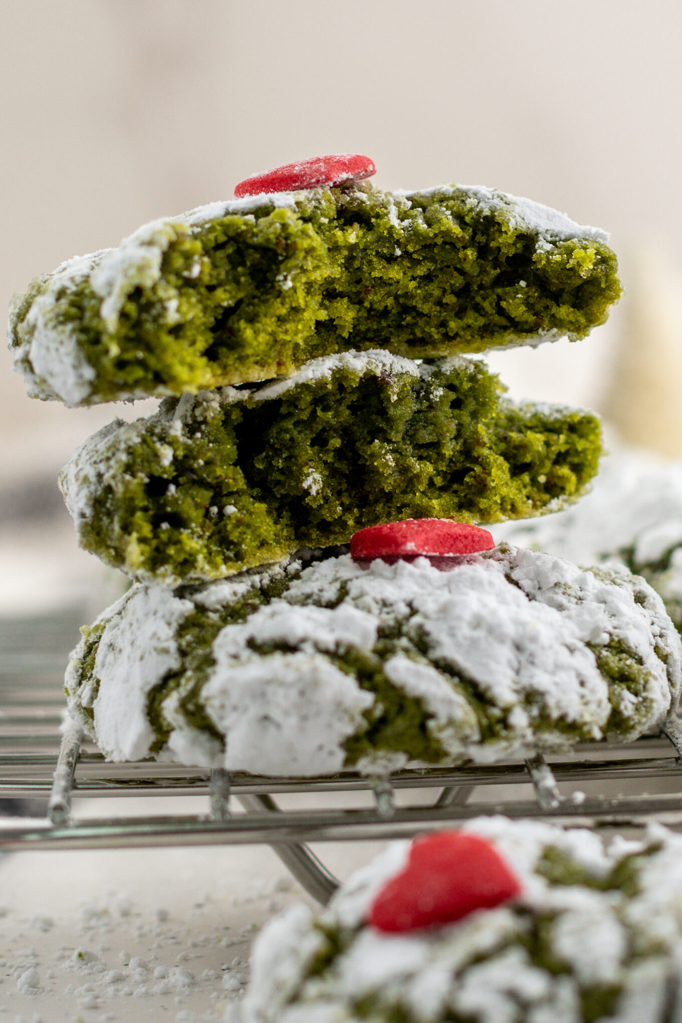 three green grinch-inspired cookies with two cut in half showing the inside.