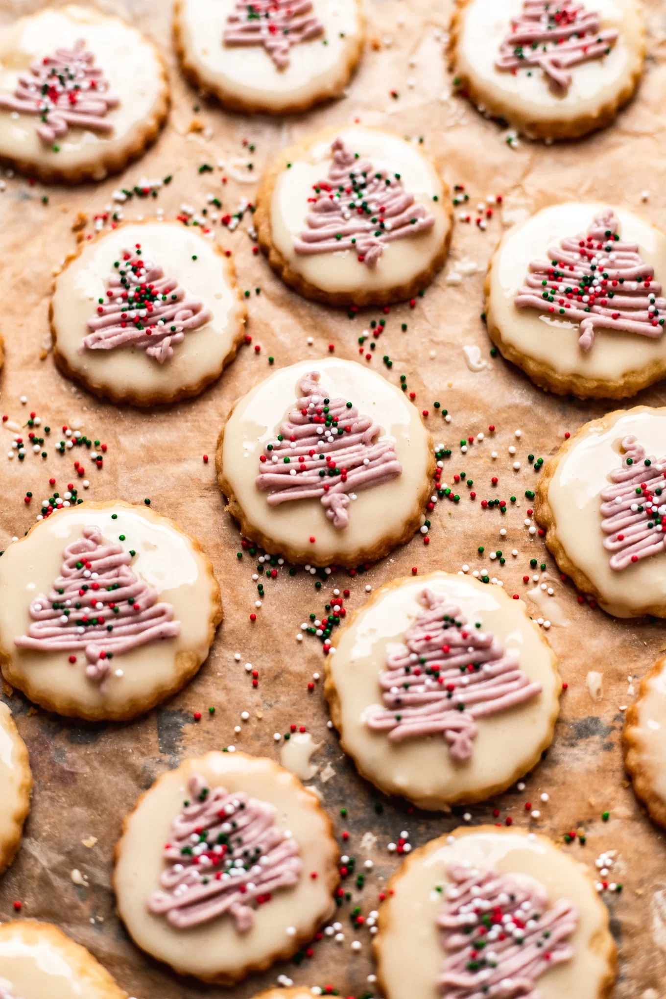 Vegan shortbread cookies decorated with frosting trees and sprinkles.