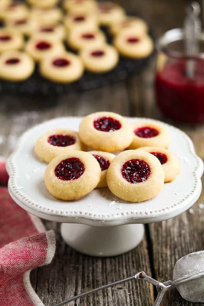 Thumbprint cookies with a jam filling on a white plate.