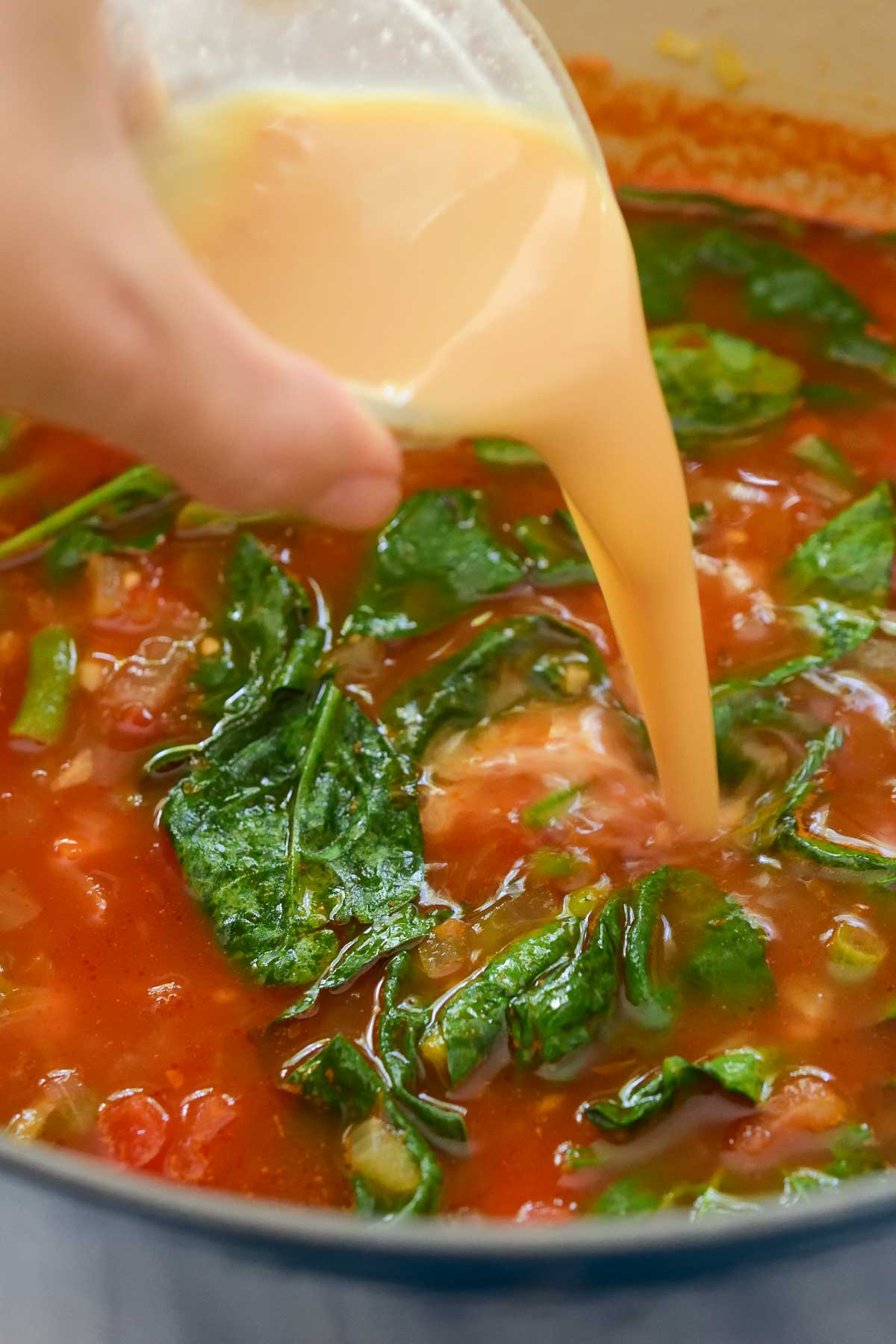 Pouring dissolved miso paste into the pot of tortellini soup.
