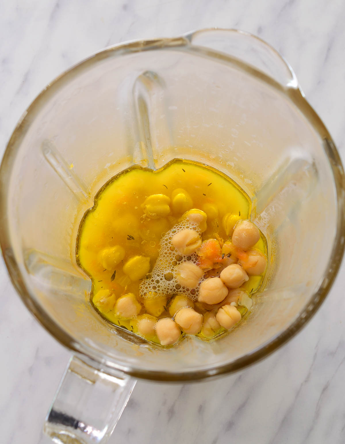Inside a blender cup with some chickpeas, lemon juice and oil.