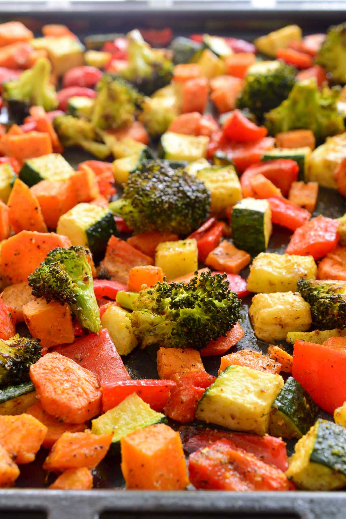 All the roasted Moroccan vegetables mixed on a black baking pan.