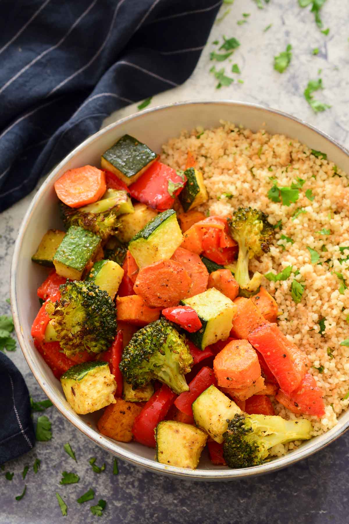 An overheat photo of Moroccan roasted vegetables in a grey ceramic bowl with couscous.