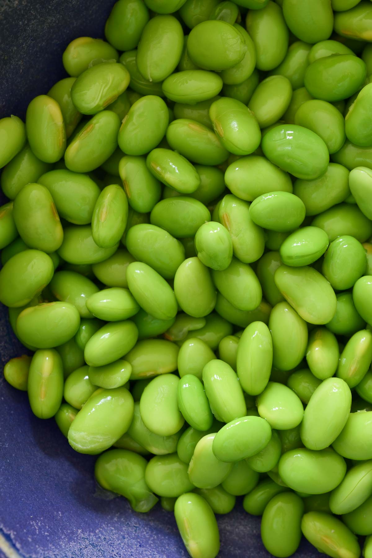 A close-up image of shelled edamame beans in a blue bowl.