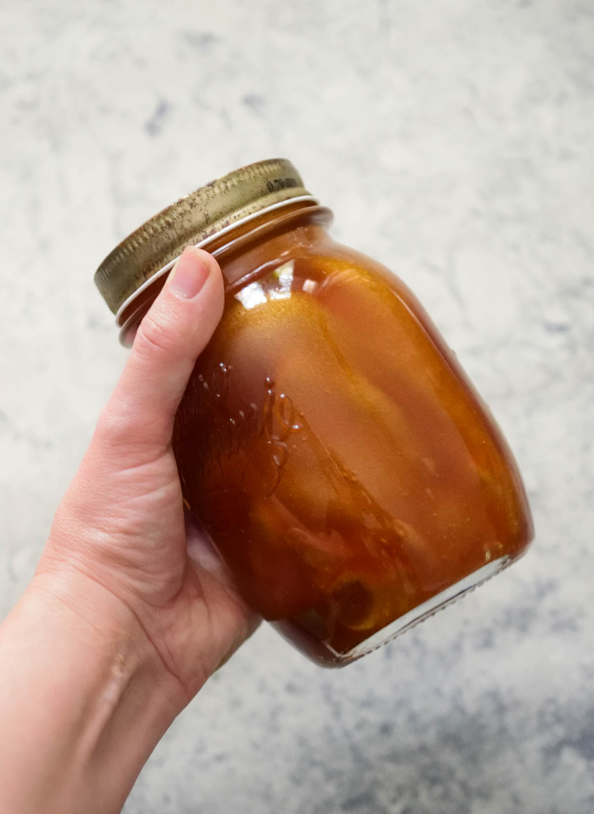 A hand is shaking the mason jar with the ingredients for Asian sesame dressing inside.