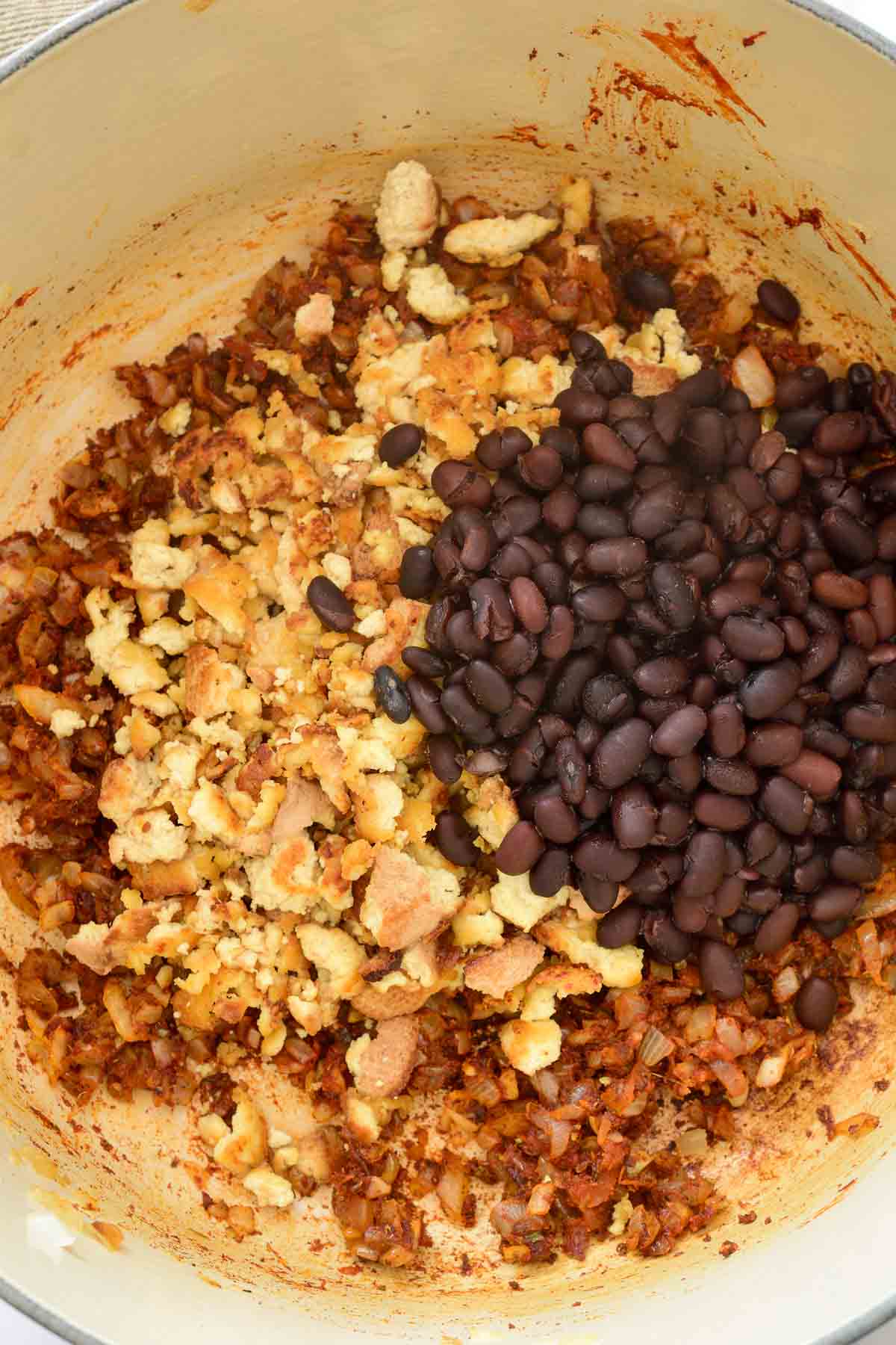 A white pot with black beans and crumbled tofu inside.