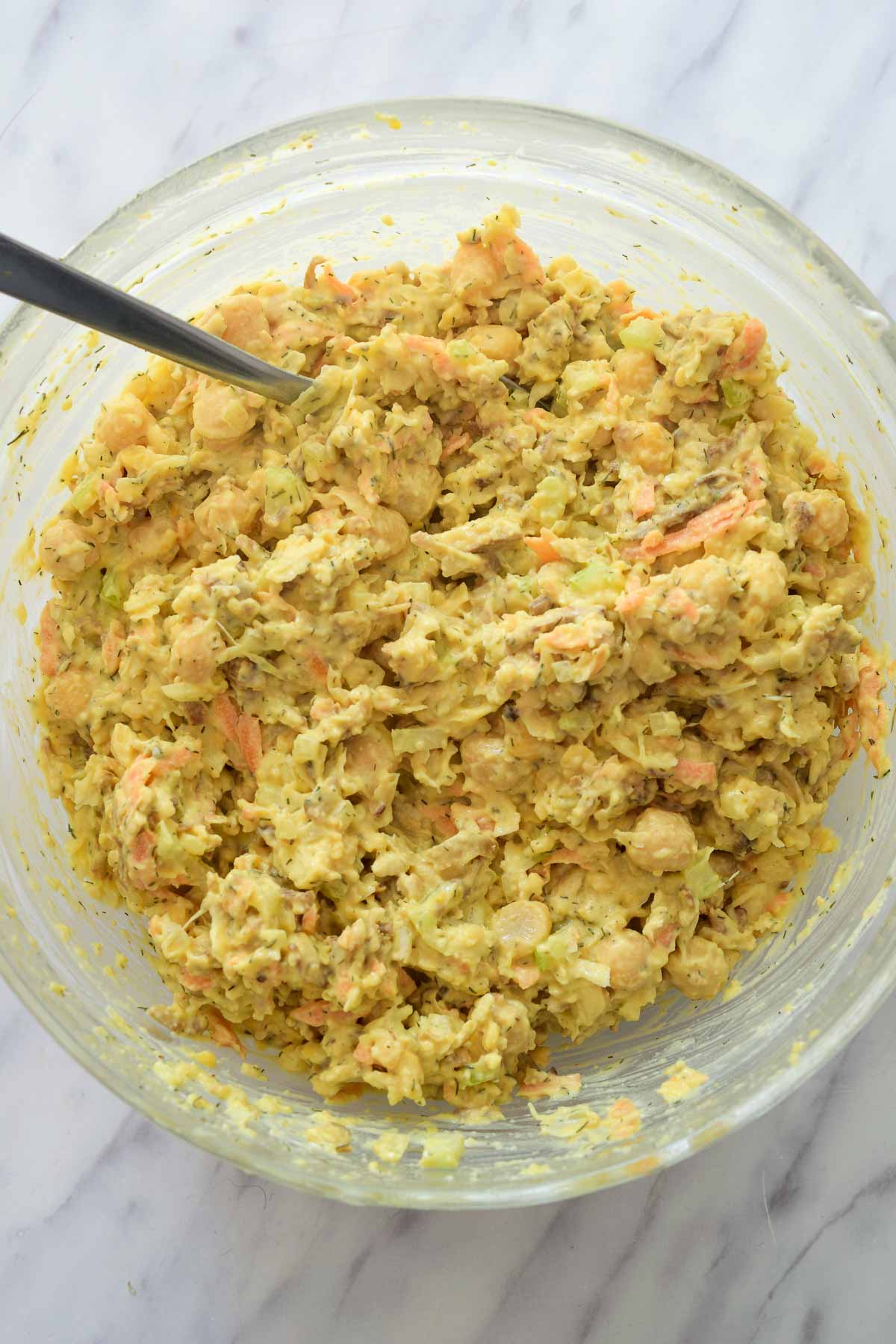 The glass bowl filled with smashed chickpea salad.