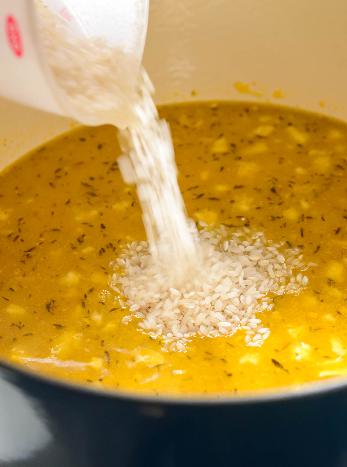 Pouring dried rice into the pot of soup.