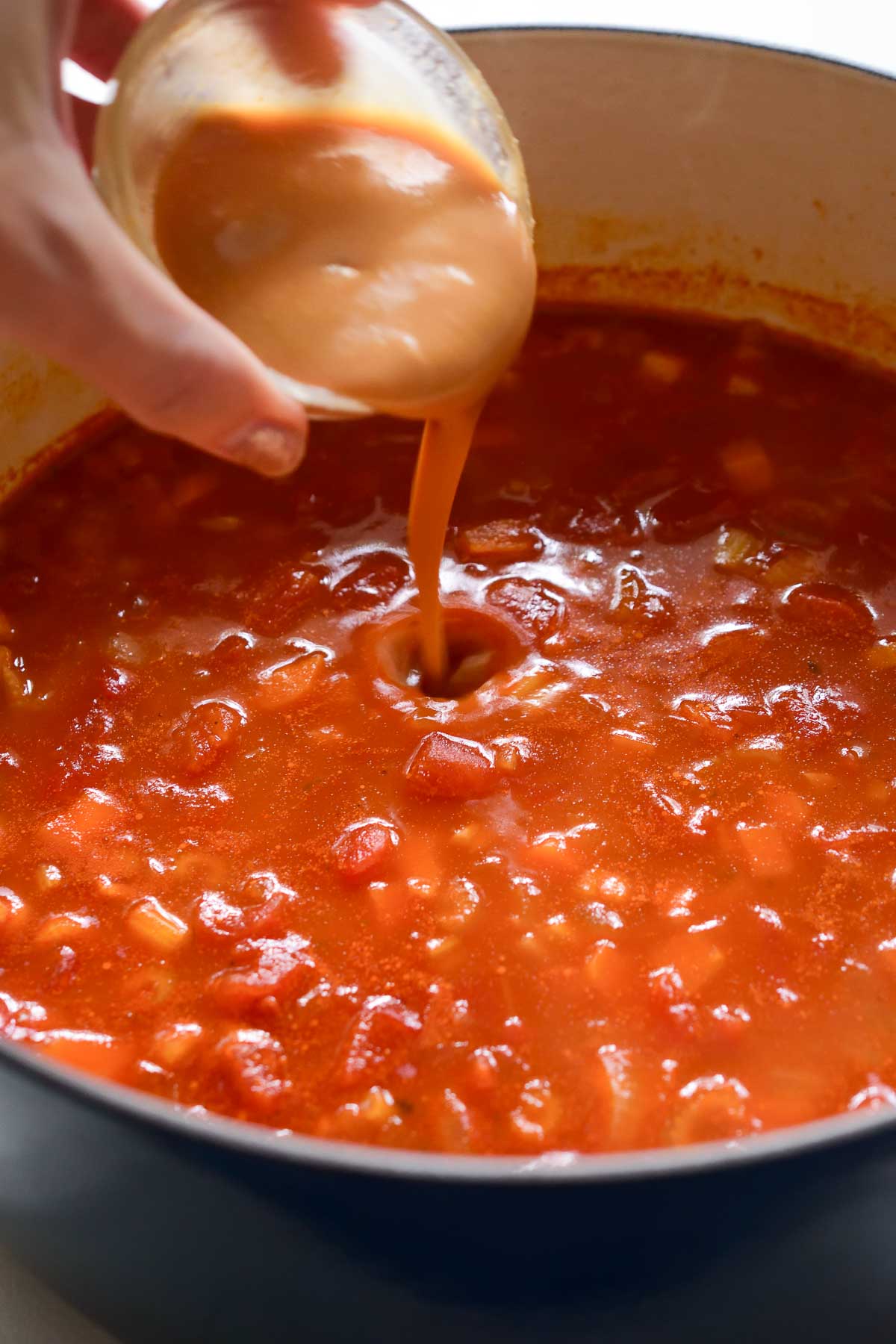 Pouring dissolved miso paste into a pot of bean and barley soup.